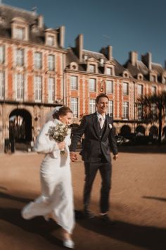 a bride and groom walking in front of an old building