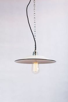 a white light hanging from a ceiling with a black cord attached to the lamp fixture