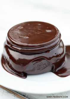 a jar filled with chocolate sitting on top of a white table next to a spoon