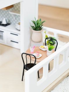 a dollhouse table with chairs and plates on it