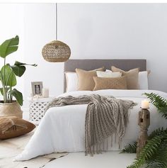 a bedroom with white brick walls and lots of greenery in the corner, including a bed