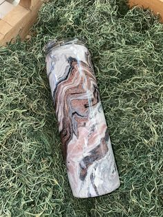 a marbled coffee cup sitting on top of green grass next to a wooden box