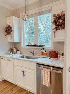 a kitchen with white cabinets and stainless steel dishwasher