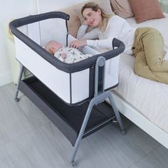 a woman laying in bed next to a baby crib with a sleeping baby on it