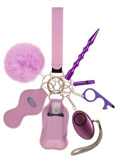 a pink keychain with various accessories including a pom - pom and a pair of scissors