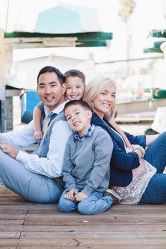 a family is sitting on the ground with their arms around each other and smiling at the camera