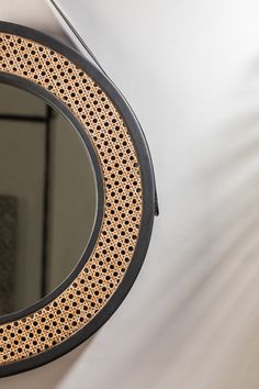 a round mirror hanging on the wall next to a white wall with a black frame