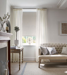 a living room filled with furniture and a window covered in white drapes next to a fire place