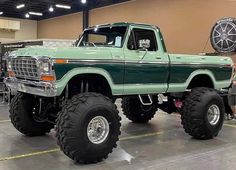 a large green truck parked inside of a garage next to a clock on the wall