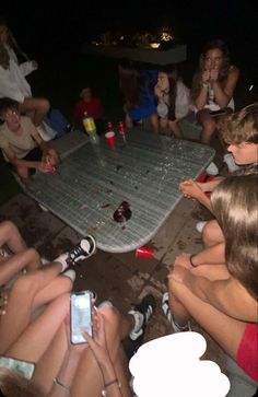 a group of people sitting around a table with drinks and cell phones in their hands