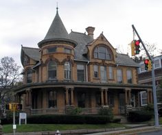 an old victorian style house on the corner of a street with a traffic light in front of it