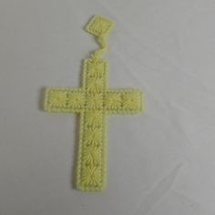 a crocheted yellow cross on a white surface