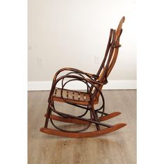 a wooden rocking chair sitting on top of a hard wood floor next to a white wall