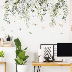 a desk with a computer and plants on it