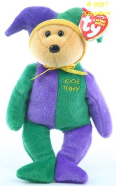 a purple and green teddy bear with a yellow tag on it's neck, wearing a hat