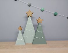 three wooden christmas trees with gold stars on them, one is green and the other is grey