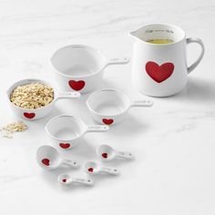 the measuring cups are filled with oatmeal and heart - shaped spoons