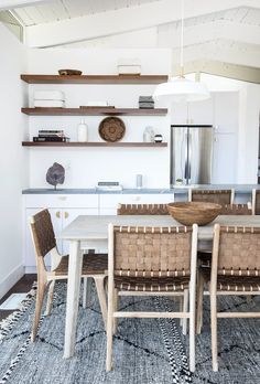 a dining room table with chairs and shelves above it