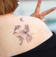 a woman with a tattoo on her back showing the peace sign and two dolphins in the water