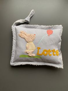 a small pillow with a teddy bear on it's back and the words lotte written in large letters