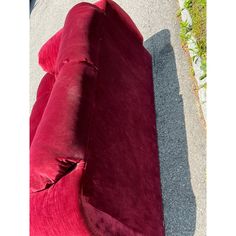 a red couch sitting on top of a sidewalk