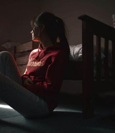 a woman sitting on the floor in front of a bed