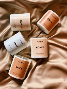 three different types of candles sitting on top of a bed next to each other with the words honey printed on them