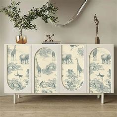 a sideboard with an animal print on it and a plant in the corner next to it