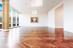 an empty room with wooden floors and large windows overlooking the cityscape in the distance