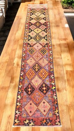 a long table with a colorful rug on it's side and stairs in the background