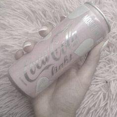 a hand holding a can of coca - cola on top of a fluffy white blanket