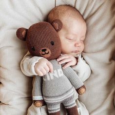 a baby sleeping with a teddy bear on top of it's back in a bed