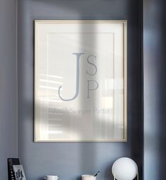 a framed monogram on the wall above a desk with a lamp and other items