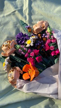 a bouquet of flowers sitting on top of a white paper bag covered in plastic wrap