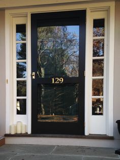 a black front door with the number 1229 on it and two candles in front