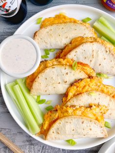 a white plate topped with tortillas and celery next to a bowl of ranch dressing