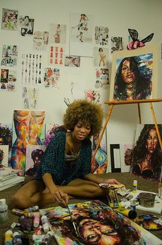 a woman is sitting on the floor in front of her art work and painting supplies