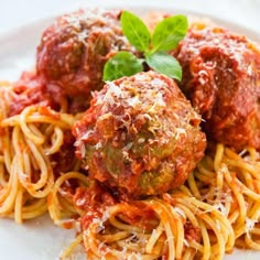 spaghetti and meatballs on a white plate with basil garnished in parmesan sauce