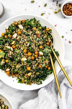 a white bowl filled with salad and two gold spoons