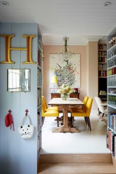 a dining room table with yellow chairs and bookshelves in front of the door