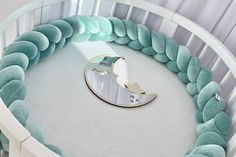 a circular bed with blue and white pillows on it's sides, next to a round mirror