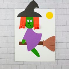 a paper cut out of a witch on a broom with orange hair and green eyes