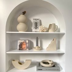 some white shelves with vases and pictures on them