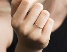 a woman is holding her hand up to the camera and wearing a gold ring with two diamonds on it