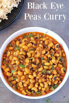 black eye peas curry in a white bowl next to a plate with rice on the side