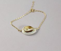 "Beautiful Cowrie (Cowry) Shell bracelet. Natural white shell is wire wrapped to 14kt gold filled delicate cable chain. Bracelet has a 1\" extender, to make sure you can wear it in your desired way. The way I wear mine is when I have a layered look with some other bracelets, I like my bracelet slightly tighter on my wrist. If I wear my bracelet alone, I will wear it loose. It's definitely up to you. This Cowrie jewelry is perfect if you have a beach wedding or you a beach lover. TO ORDER: -Choos Casual Cowrie Shell Bracelets, White Cowrie Shell Bracelet, Cowrie Jewelry, Handmade Gold Shell-shaped Bracelet, Jewelry Gold Bracelet, Cowrie Shell Bracelet, Adjustable Gold Shell-shaped Bracelet, Bohemian Jewelry With Shell-shaped Cowrie Shell, Sea Shell Jewelry