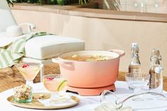 a table topped with drinks and food on top of a white table covered in plates