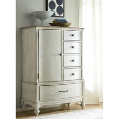 an armoire with drawers in the corner and a white rug on the floor next to it