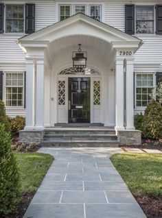 a white house with black shutters on the front door and steps leading up to it