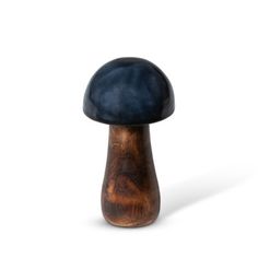 a small wooden mushroom sitting on top of a white surface with dark blue paint and wood grain